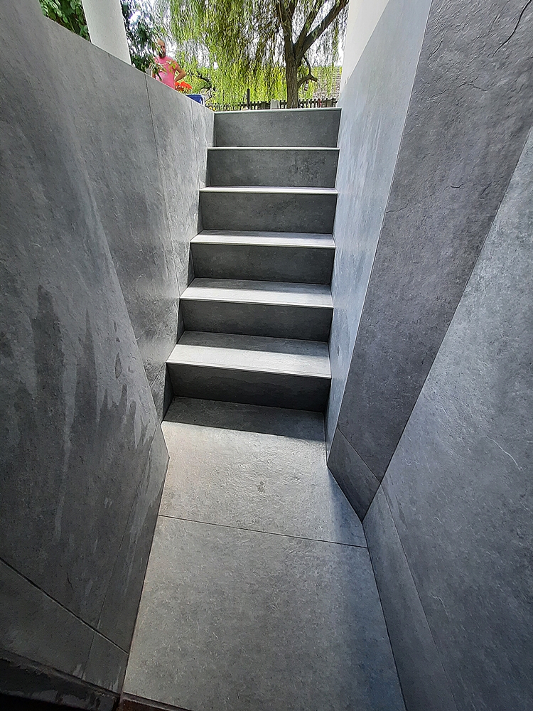 schody prowadzące poniżej poziomu gruntu wyłożone płytkami stopnie oraz ściany